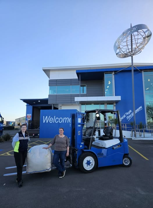 A Mainfreight manager and a Textile Rescue volunteer with a fadge of textiles on a forklift outside Mainfreight