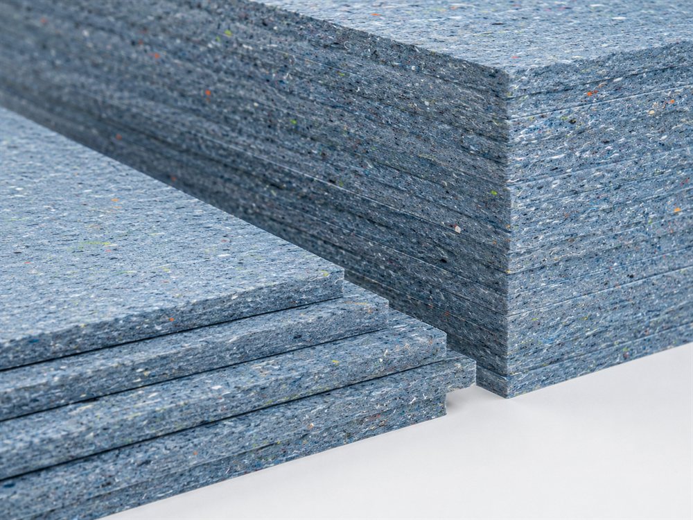 A stack of boards made from compressed recycled textiles, flecked blue-grey